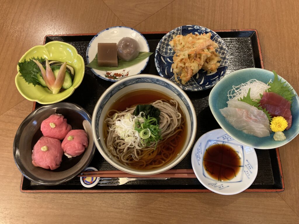 介護施設の栄養バランスの取れた食事。そば、刺身、天ぷら、野菜など。